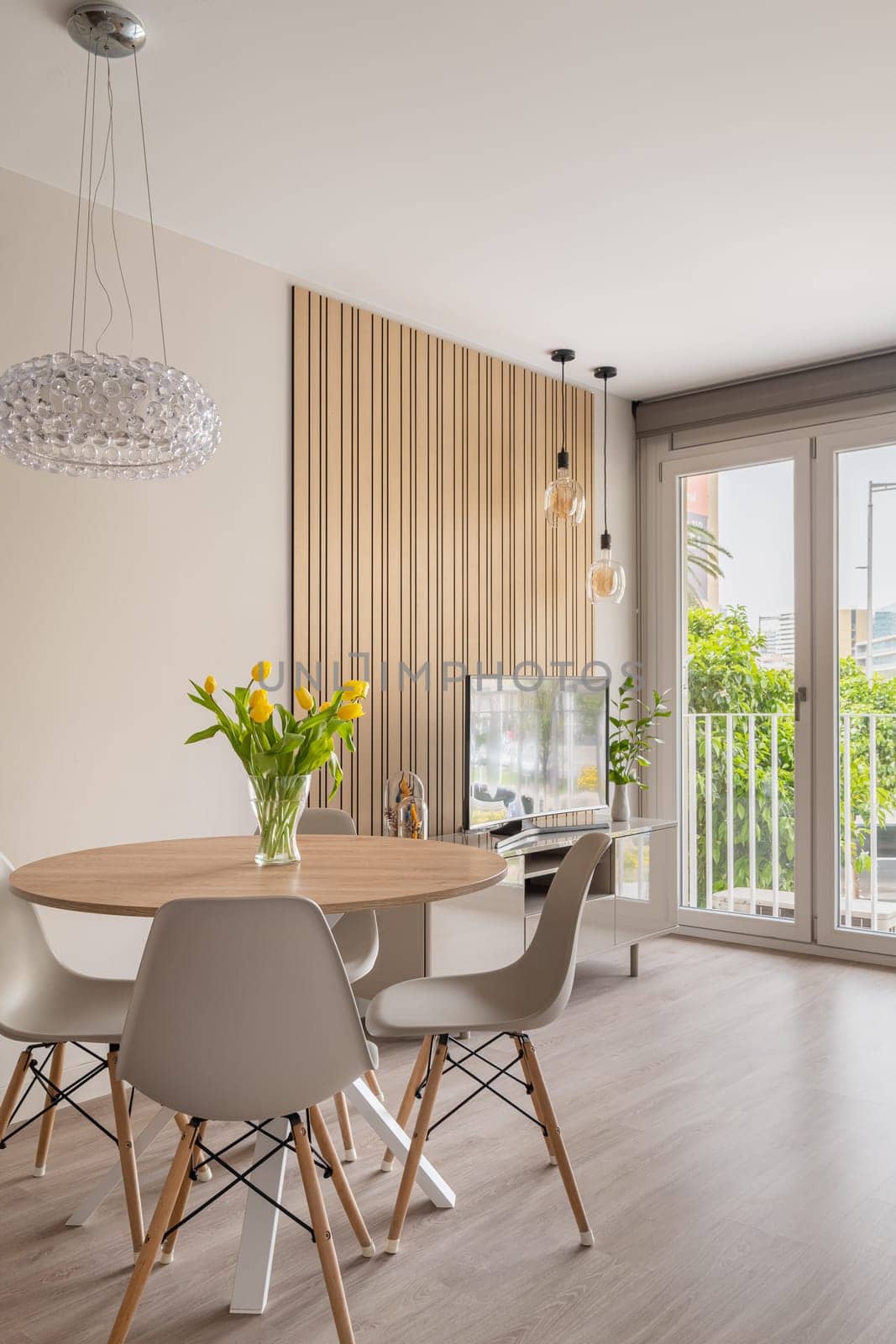 Spacious dining room with modern furniture, a striking light fixture, and a beautiful view through the balcony doors.