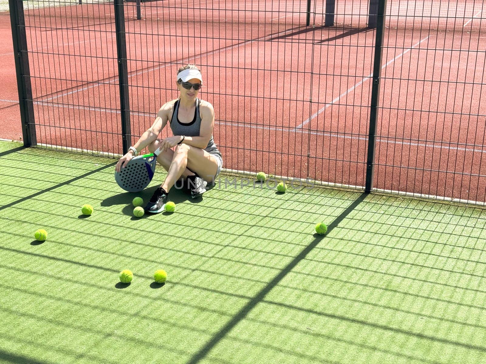 Woman playing padel in a grass padel court indoor - Young sporty woman padel player hitting ball with a racket. High quality photo