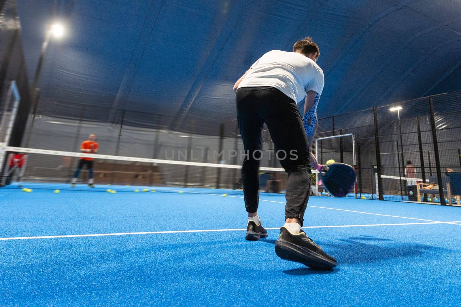 unrecognizable padel player playing padel in a padel court indoor behind the net. High quality photo