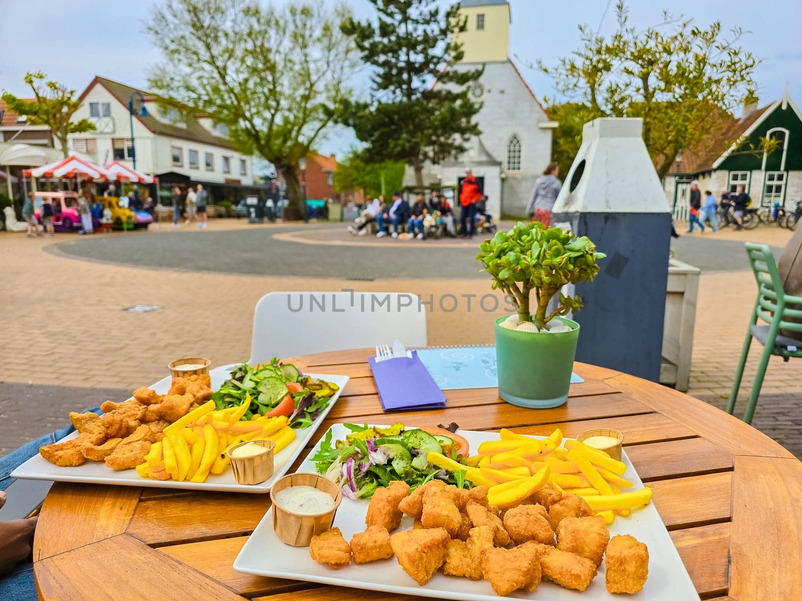 Two beautifully arranged plates of food sit on a table in the bustling town square of Texel, Netherlands, ready to be enjoyed by hungry diners.