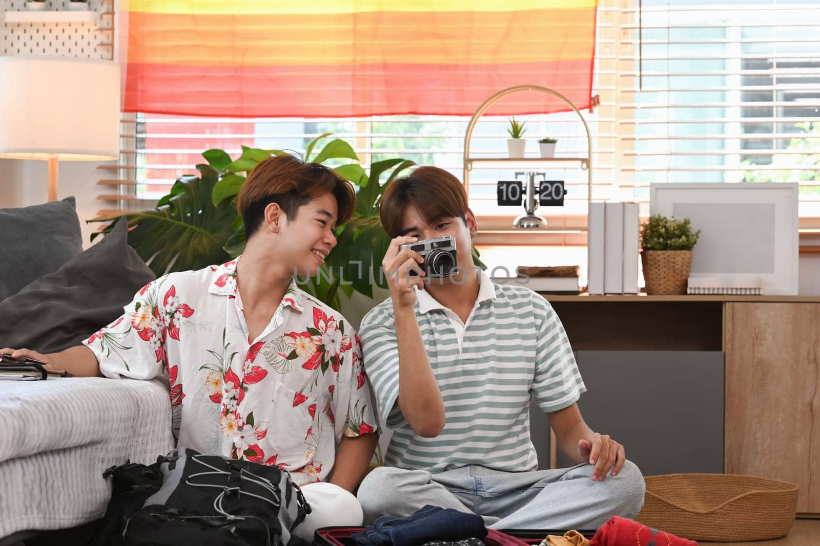 Cheerful young gay lovers preparing clothes and stuff getting ready for their vacation trip.