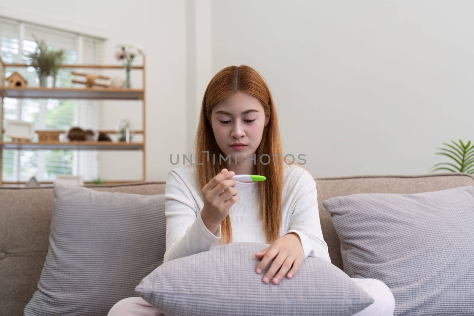 Young woman checking pregnancy test at home, feeling concerned. Concept of uncertainty and personal health.