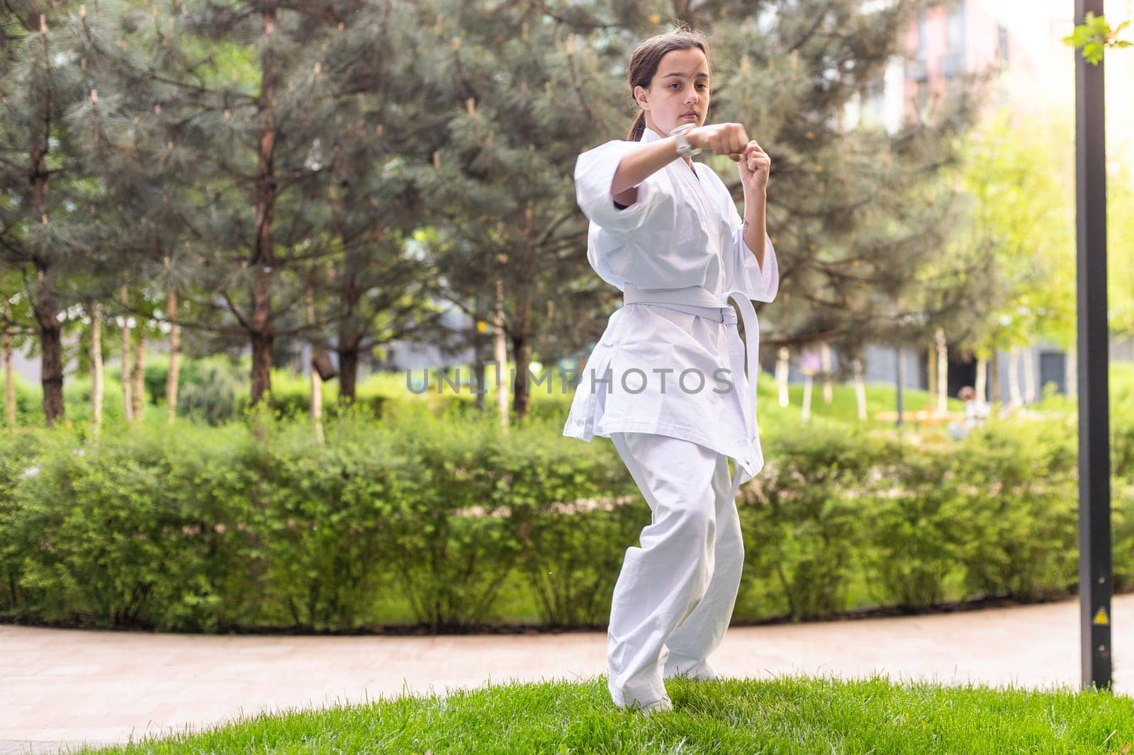 Young active girl wearing in white kimono with white belt performing martial arts kick skills. sporty karate woman improving fight technique on Chinese bridge. concept of sport. High quality photo