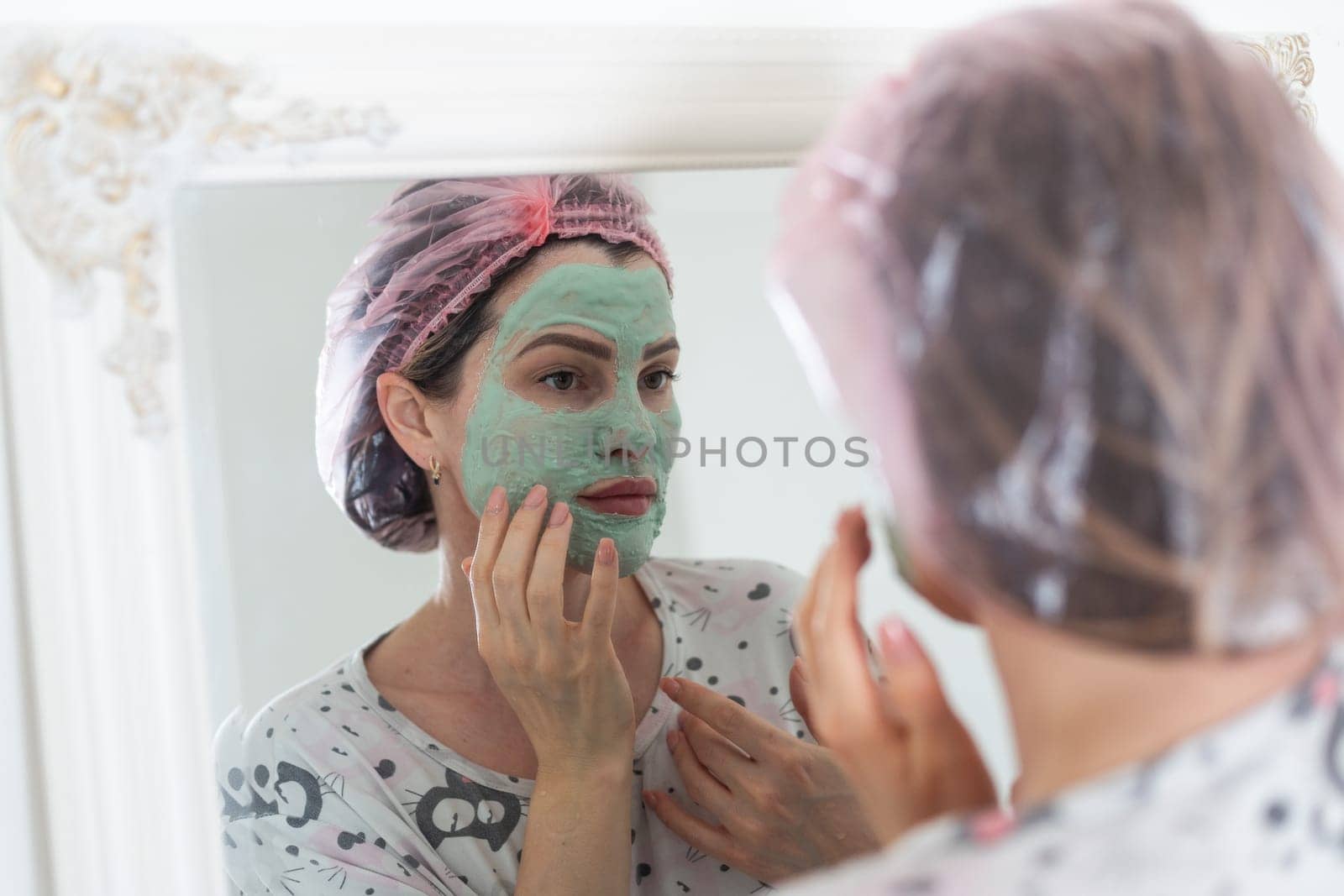 Self care: a woman applying clay mask to her face. High quality photo