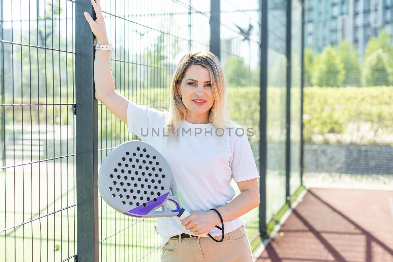 Sportive young girl with racquet playing padel in court. High quality photo