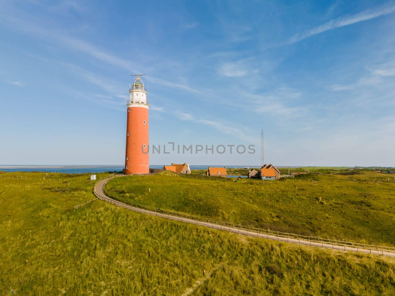 A majestic lighthouse stands tall on a grassy field, casting a watchful eye over the Texel landscape below.
