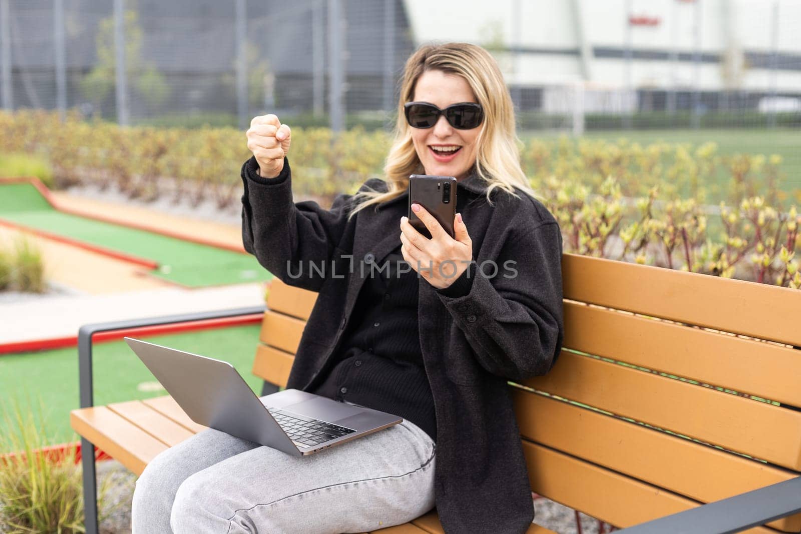 woman on golf course with smartphone with sports betting app. High quality photo