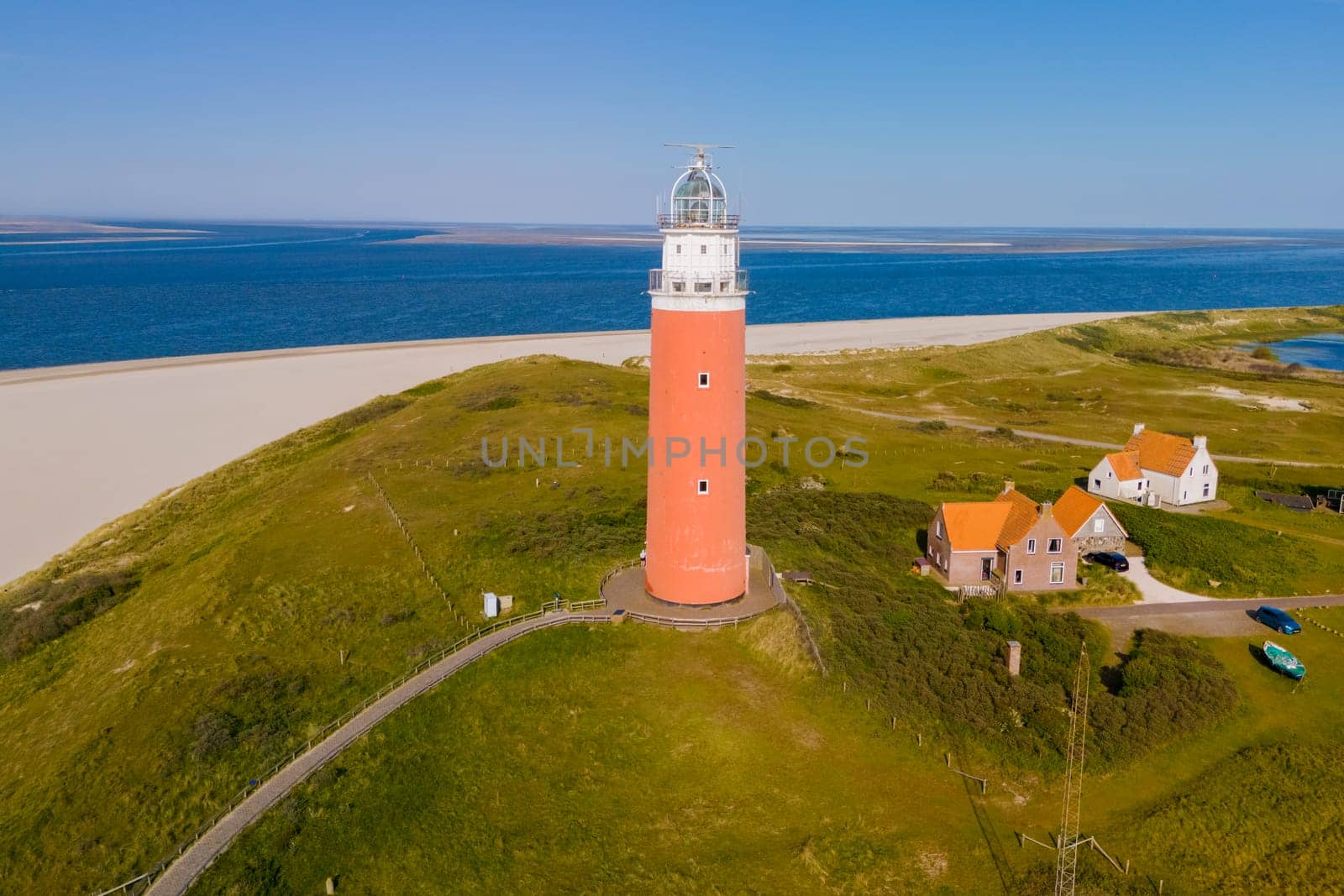 Majestic lighthouse overlooking a sandy beach, standing tall and guiding ships with its bright light.