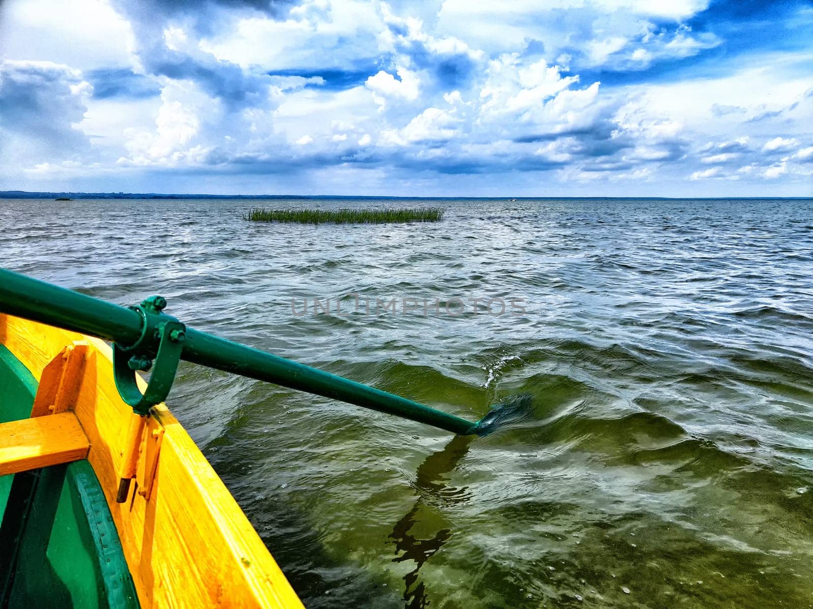 The paddle of a boat and the water of a large lake in the background. Natural landscape, travel, recreation. boat paddle extends over a calm lake