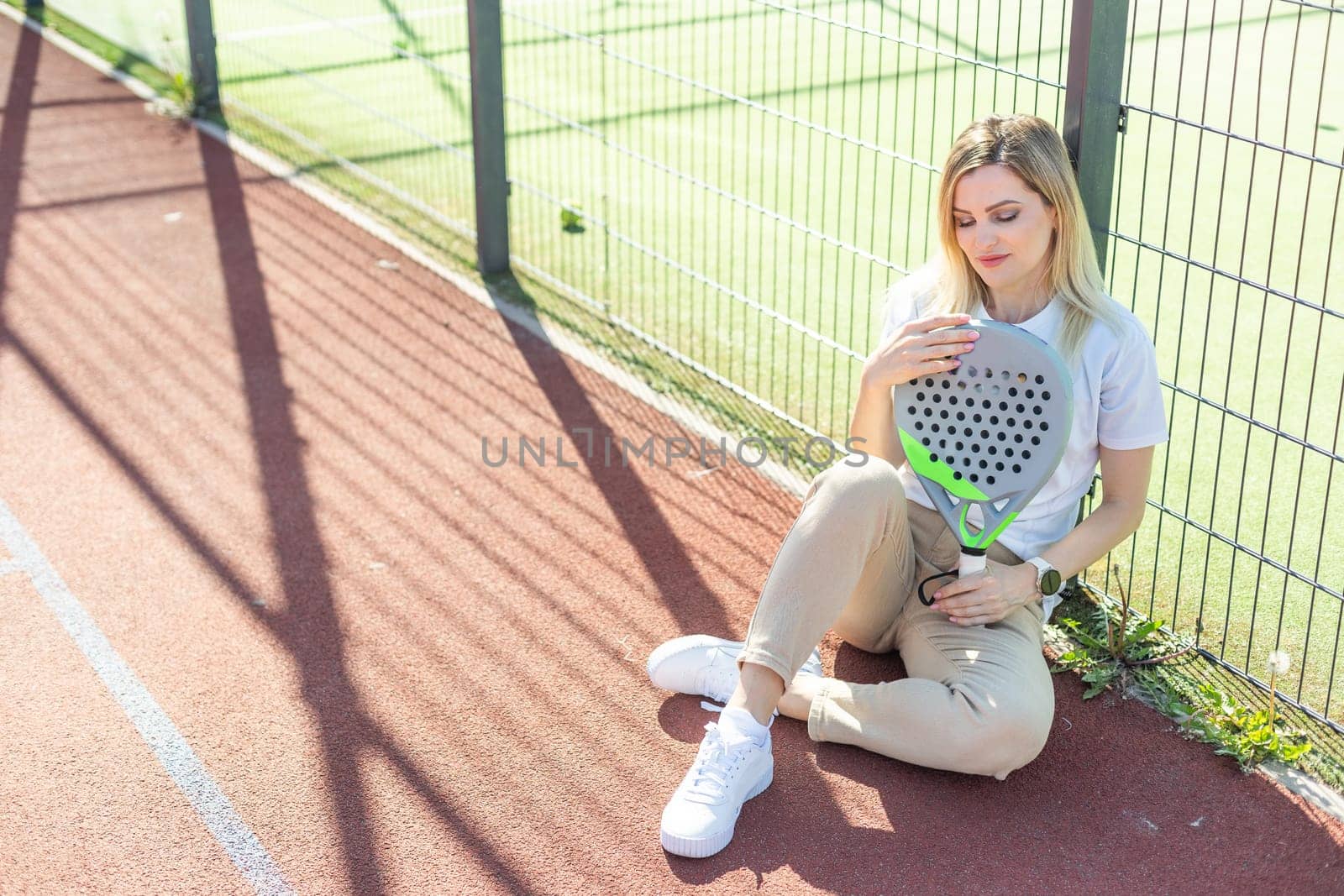 Happy female paddle tennis player during practice on outdoor court looking at camera. Copy space. High quality photo