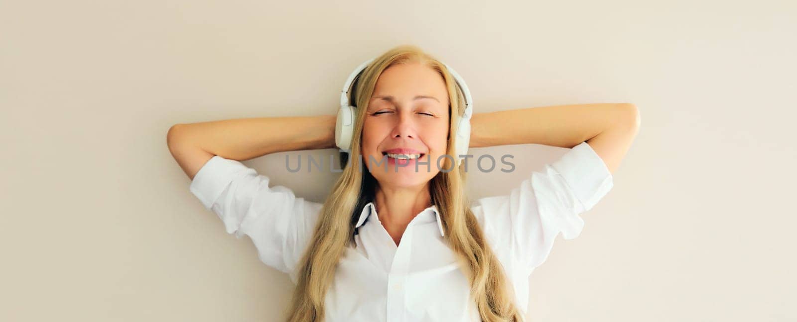 Portrait of happy relaxed middle aged woman listening to music with headphones by Rohappy