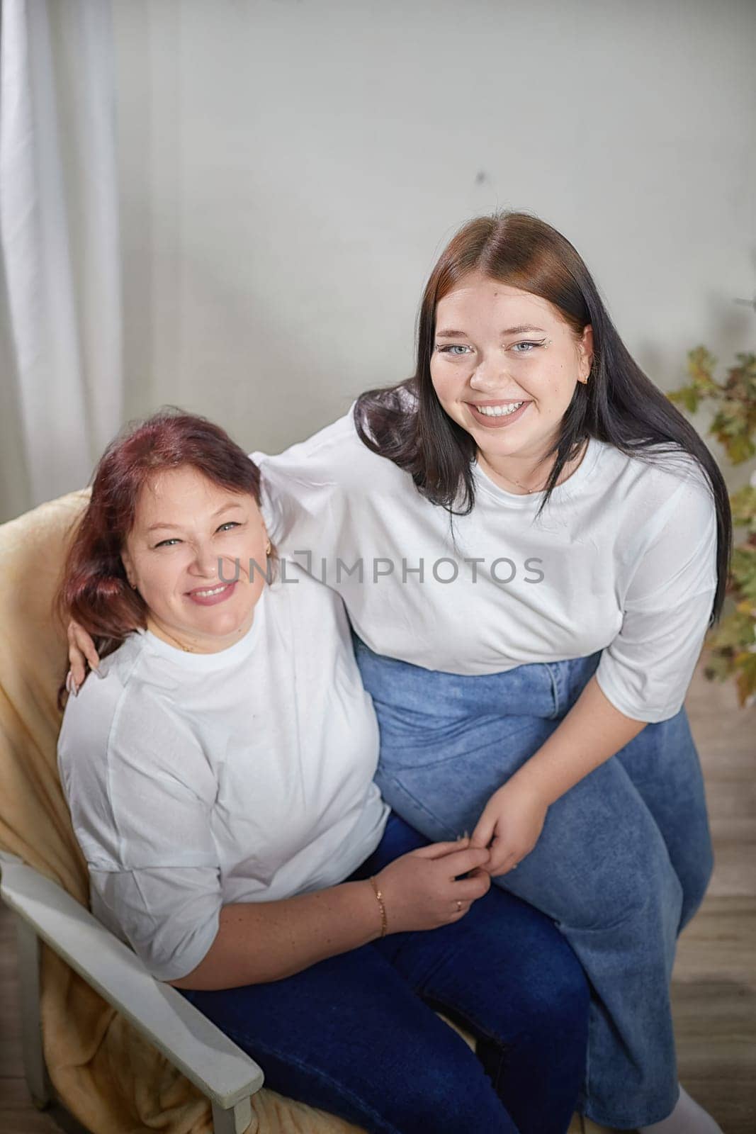 Happy Overweight family with mother and daughter in room. Middle aged woman and teenager girl having fun, joy, hugging by keleny