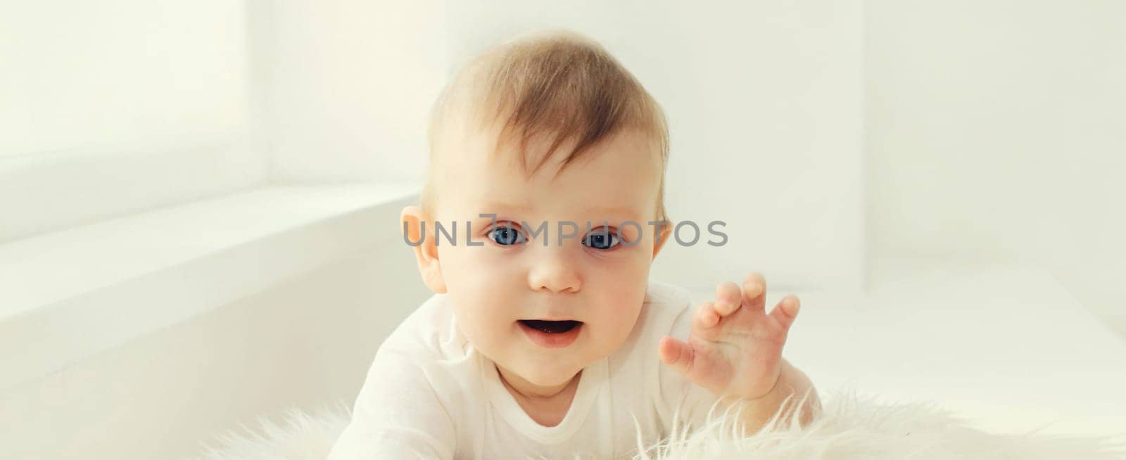 Portrait of cute little baby crawling on the floor in white room at home