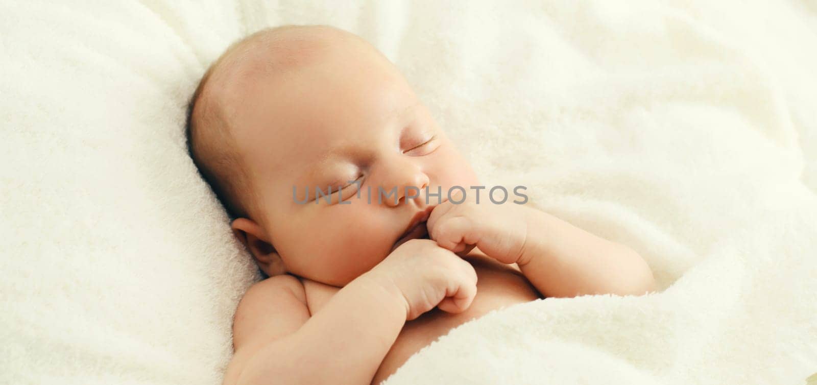 Close up portrait of infant sweet sleeping lying on white bed at home