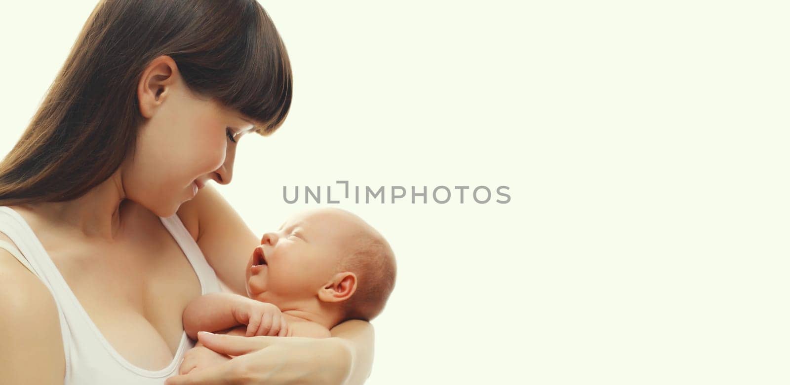 Happy mother holding cute infant, baby sleeping in arms on white studio background by Rohappy