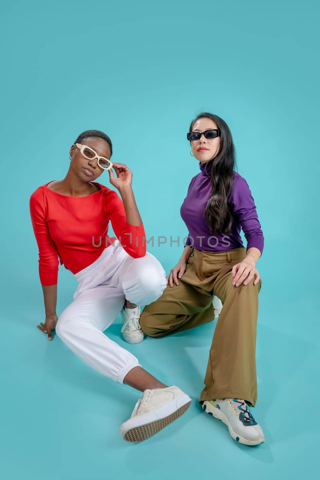 Two young beautiful smiling hipster female in trendy clothes. Sexy carefree women posing in wall in studio. Positive models having fun. Cheerful and happy. In sunglasses. High quality photo