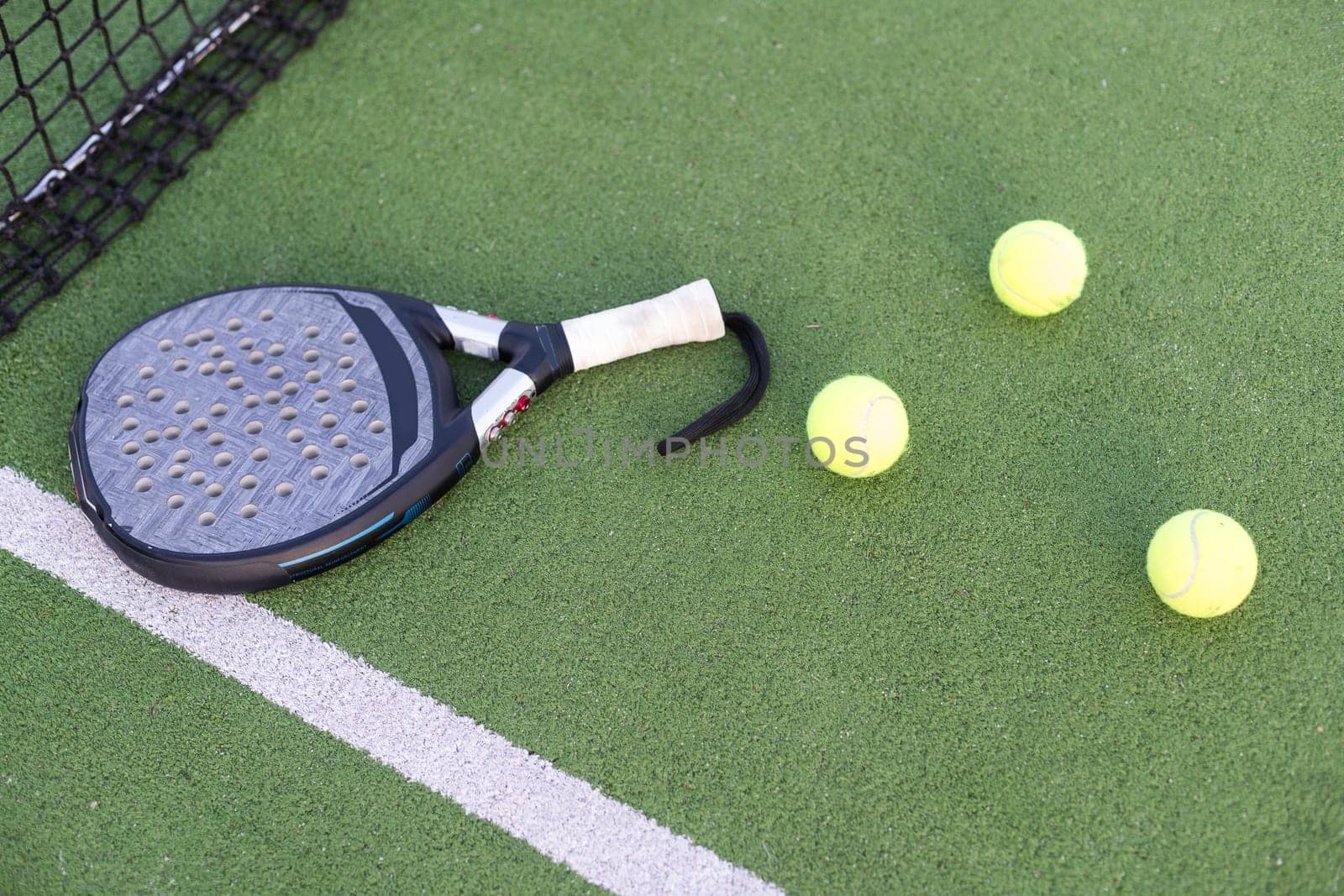 Paddle tennis racket, ball and net on the grass . High quality photo