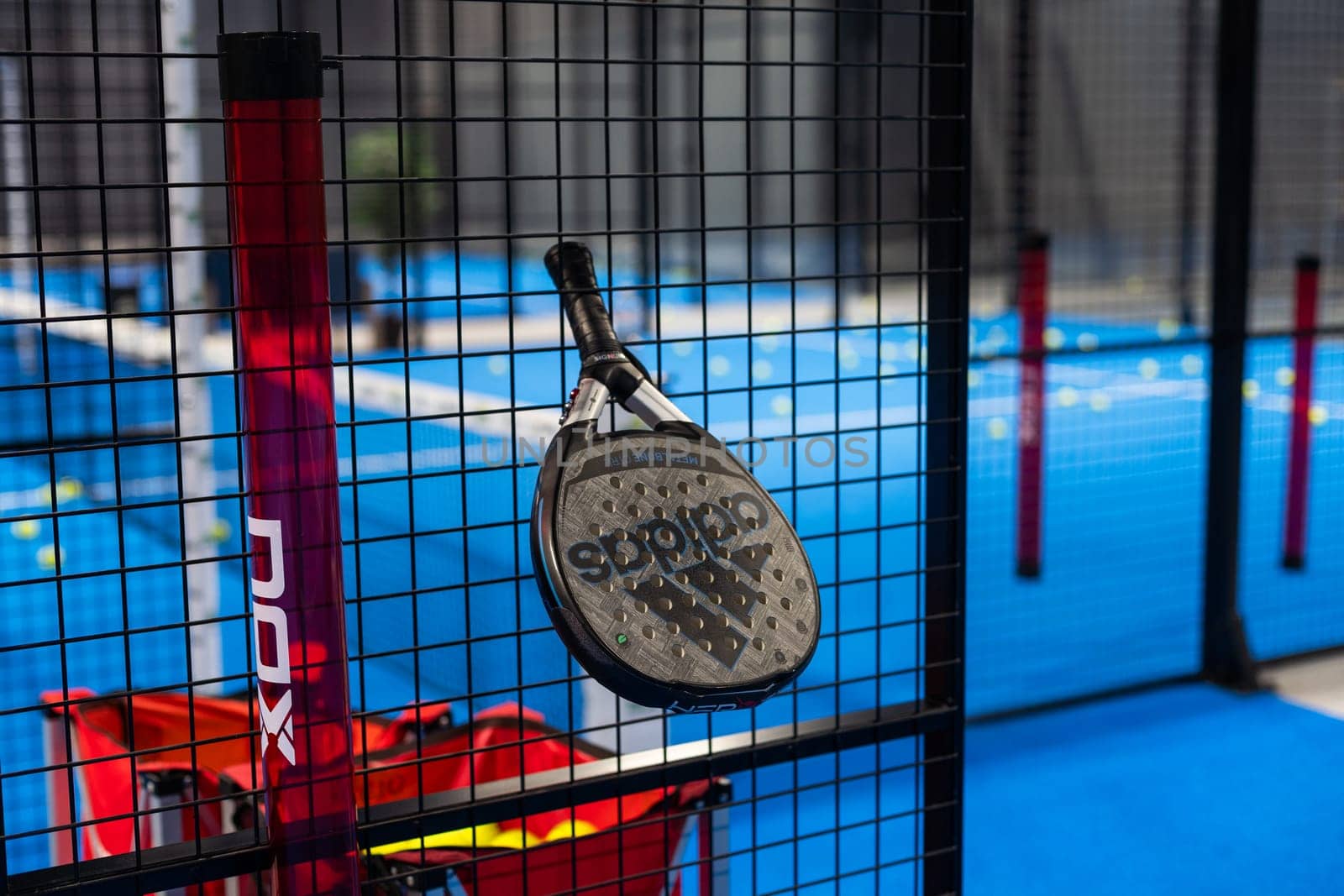 Kyiv, Ukraine, April 18, 2024. Black professional paddle tennis racket and ball with natural lighting on blue background. Horizontal sport theme poster, greeting cards, headers, website and app. High quality photo