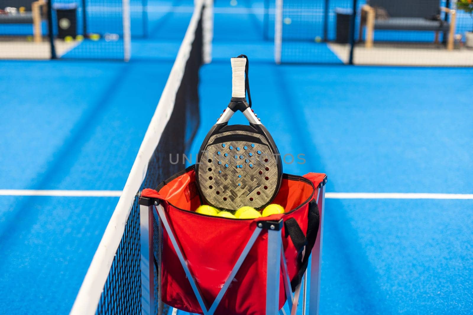 Paddle tennis: Padel racket and ball in front of an outdoor court. High quality photo