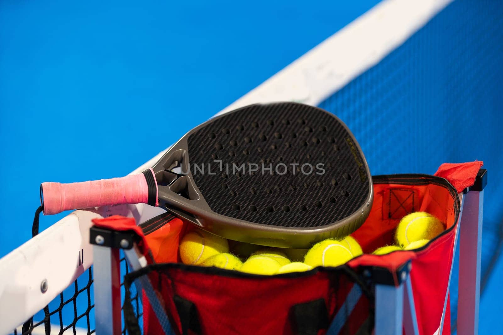 balls near the net of a blue padel tennis court. High quality photo