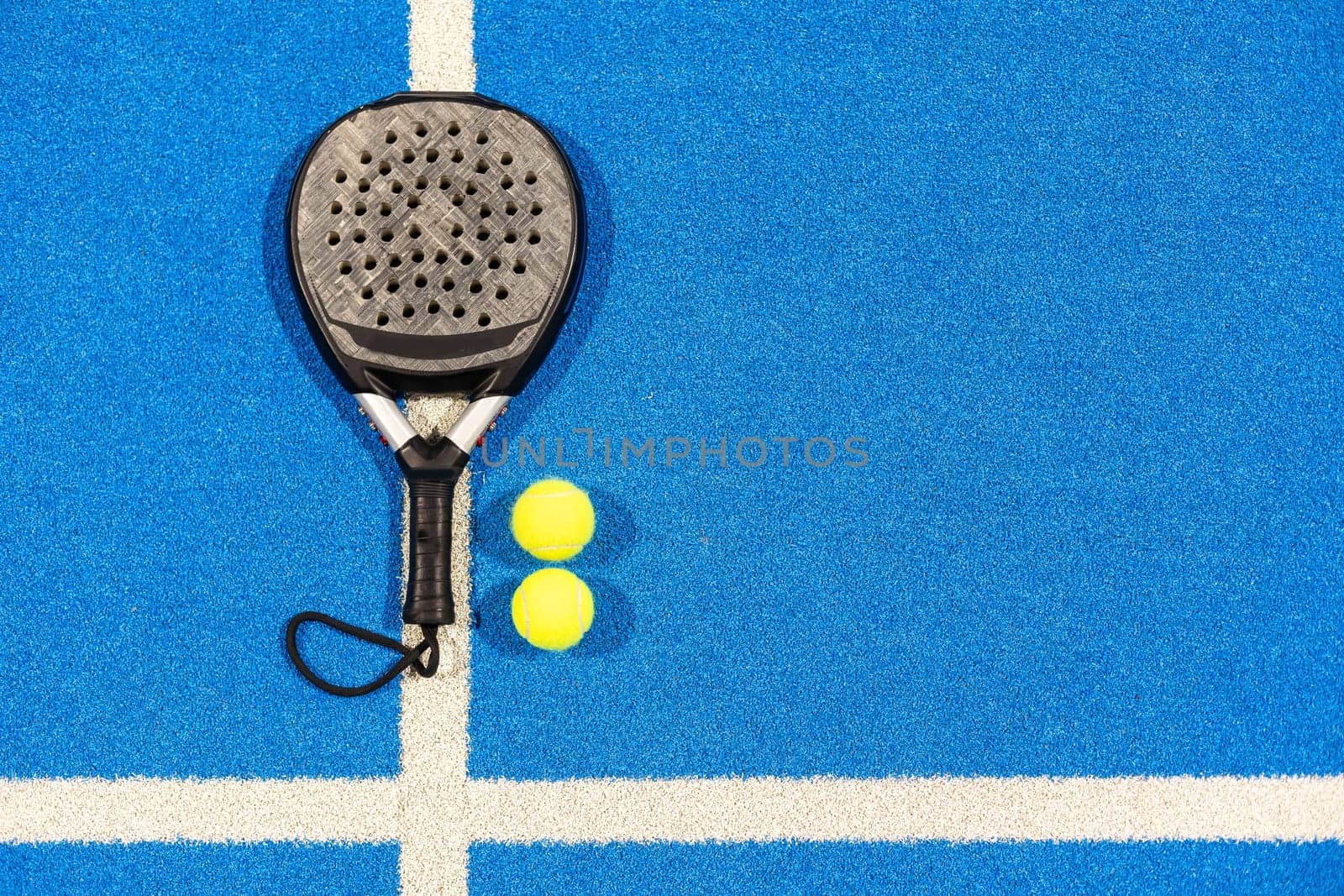 Black professional paddle tennis racket and ball with natural lighting on blue background. Horizontal sport theme poster, greeting cards, headers, website and app. High quality photo