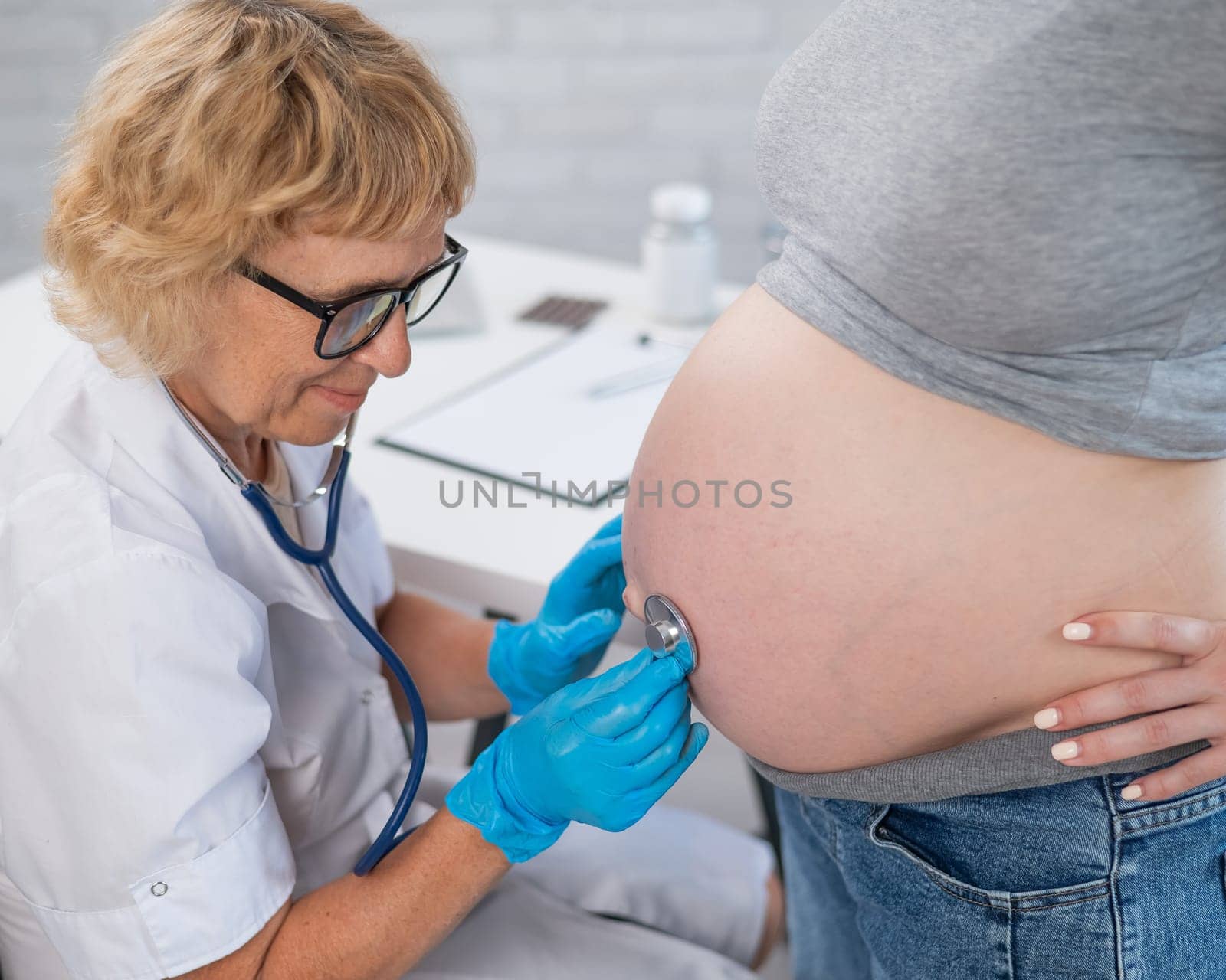 The doctor listens to the heartbeat of the baby of a pregnant woman
