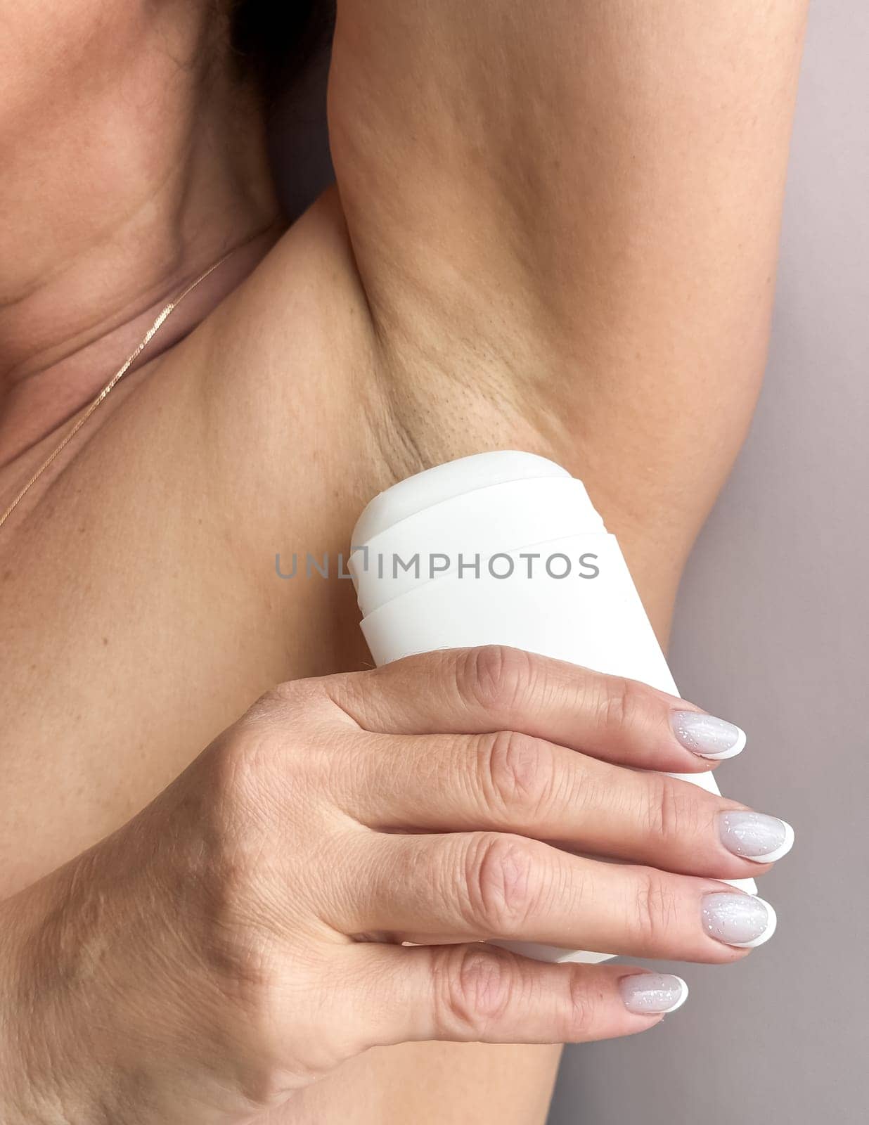 Close up of woman middle age applying deodorant to armpit. Personal hygiene and body care concept. Design for skincare, beauty, wellness, and health poster. High quality photo