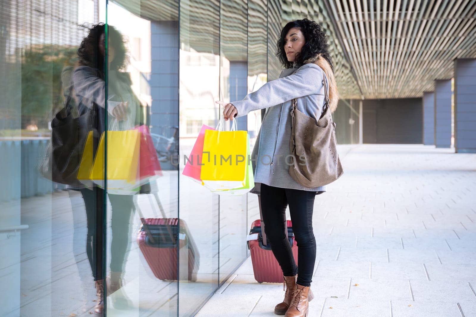 Woman shopping in the mall pointing new clothes at the window, showing a good discount price offer.