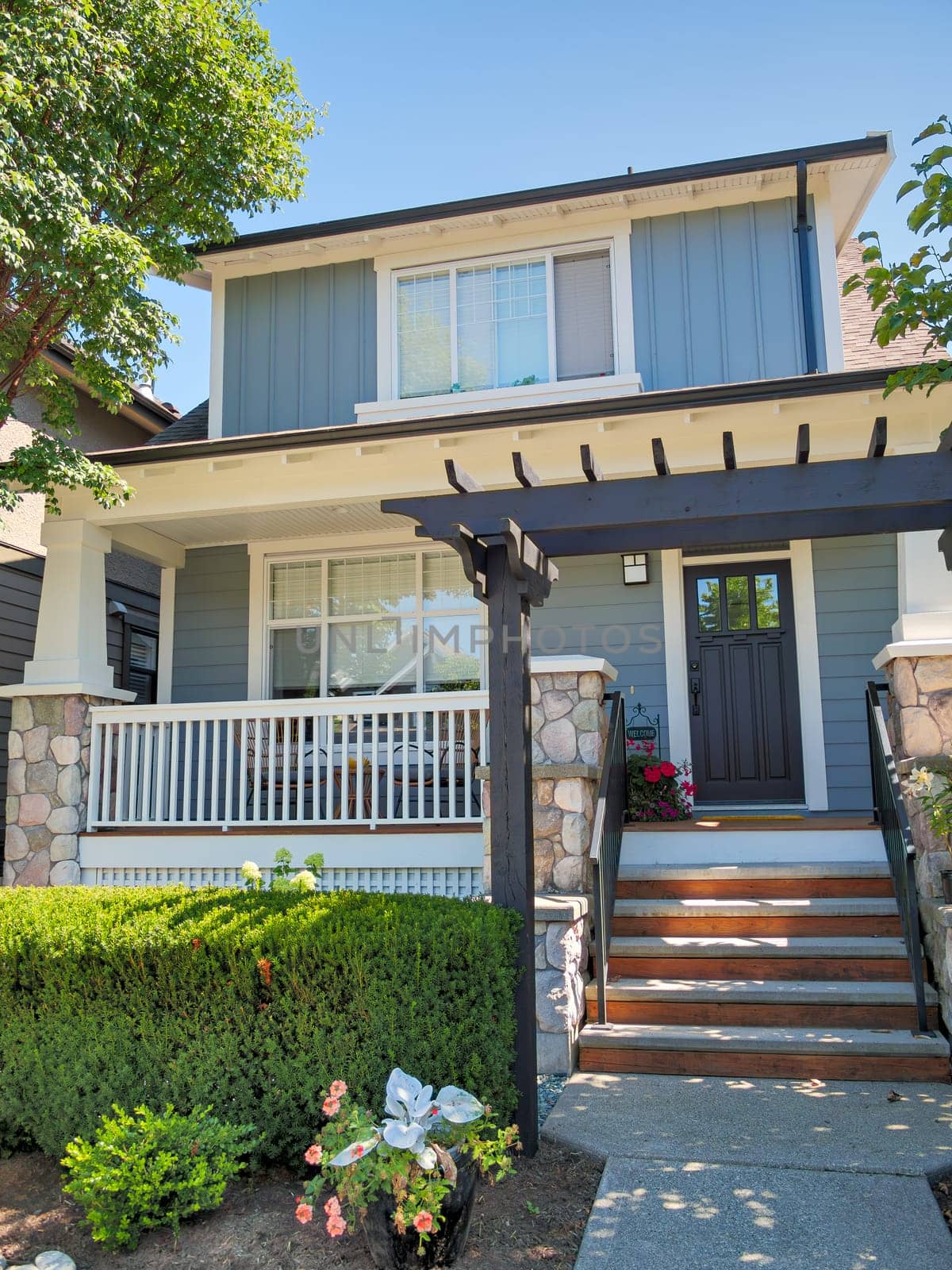 A perfect neighbourhood. The porch and entrance of a lovely residential house against a blue sky background