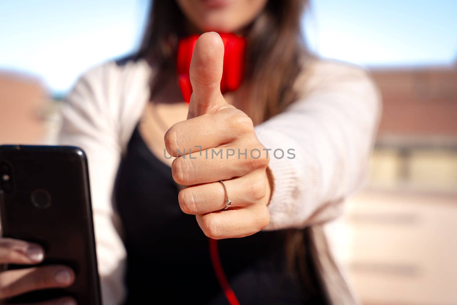 Unrecognizable business woman pointing finger up looking at camera outdoors by mariaphoto3