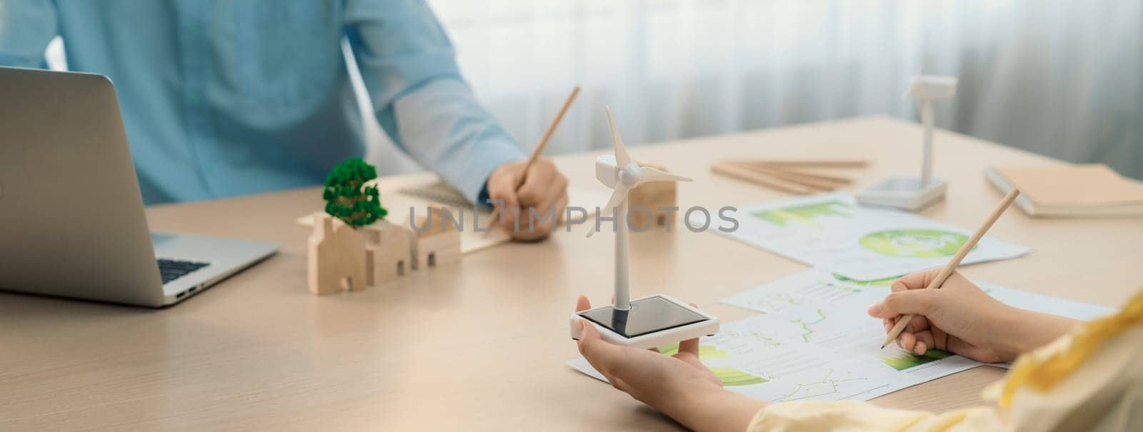 Windmill model was holding by skilled businesswoman while she start represented about benefit of using renewable energy for green business on the meeting table. Closeup. Delineation.