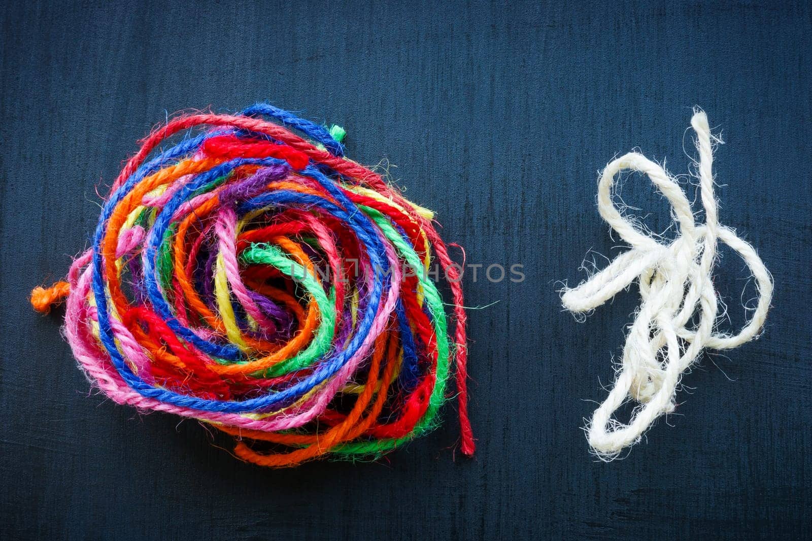 A ball of colored threads and regular one next to it as a symbol of teamwork and collaboration.