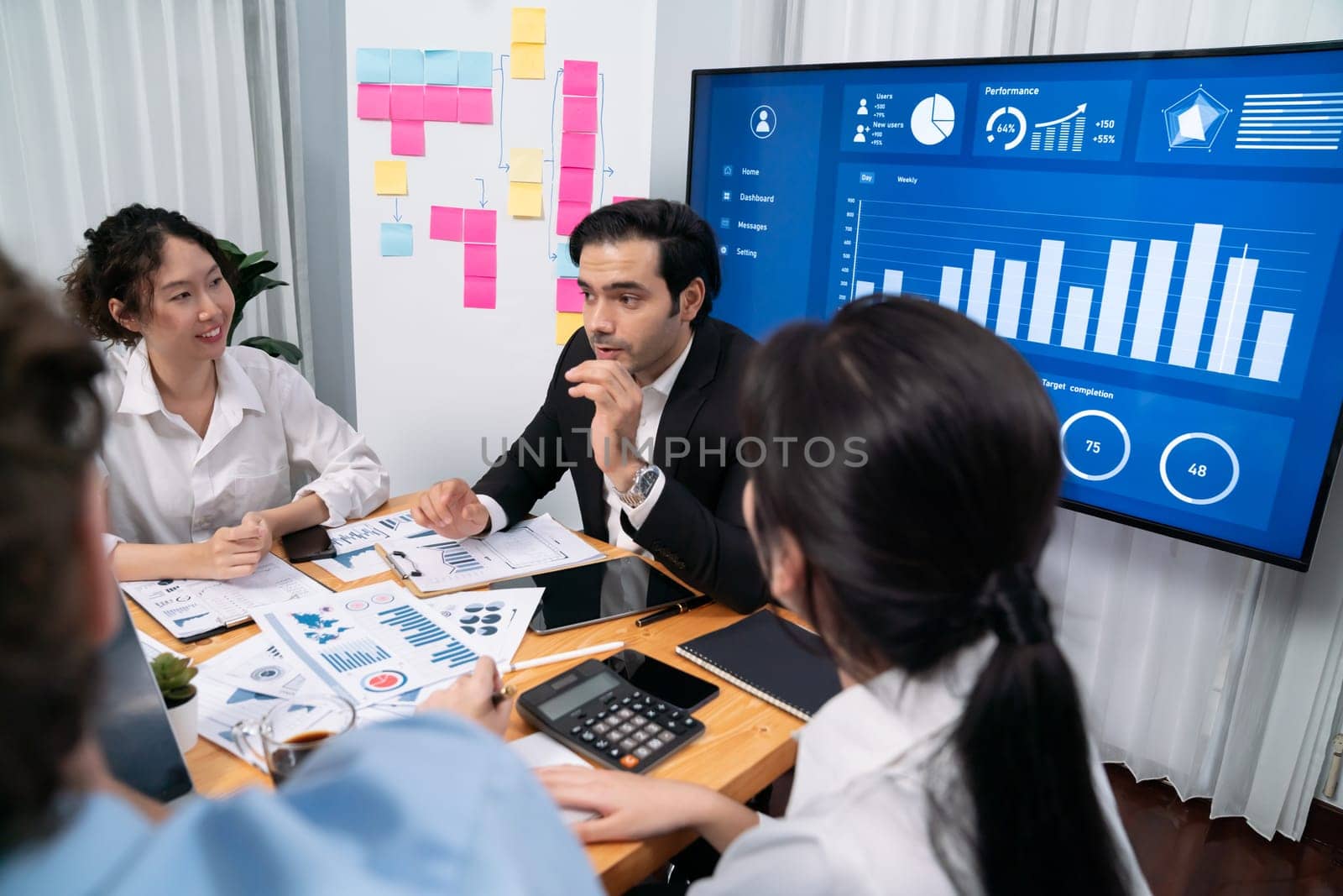 Diverse group of business analyst team analyzing financial data report. Finance data analysis chart and graph dashboard show on TV screen in meeting room for strategic marketing planning. Habiliment