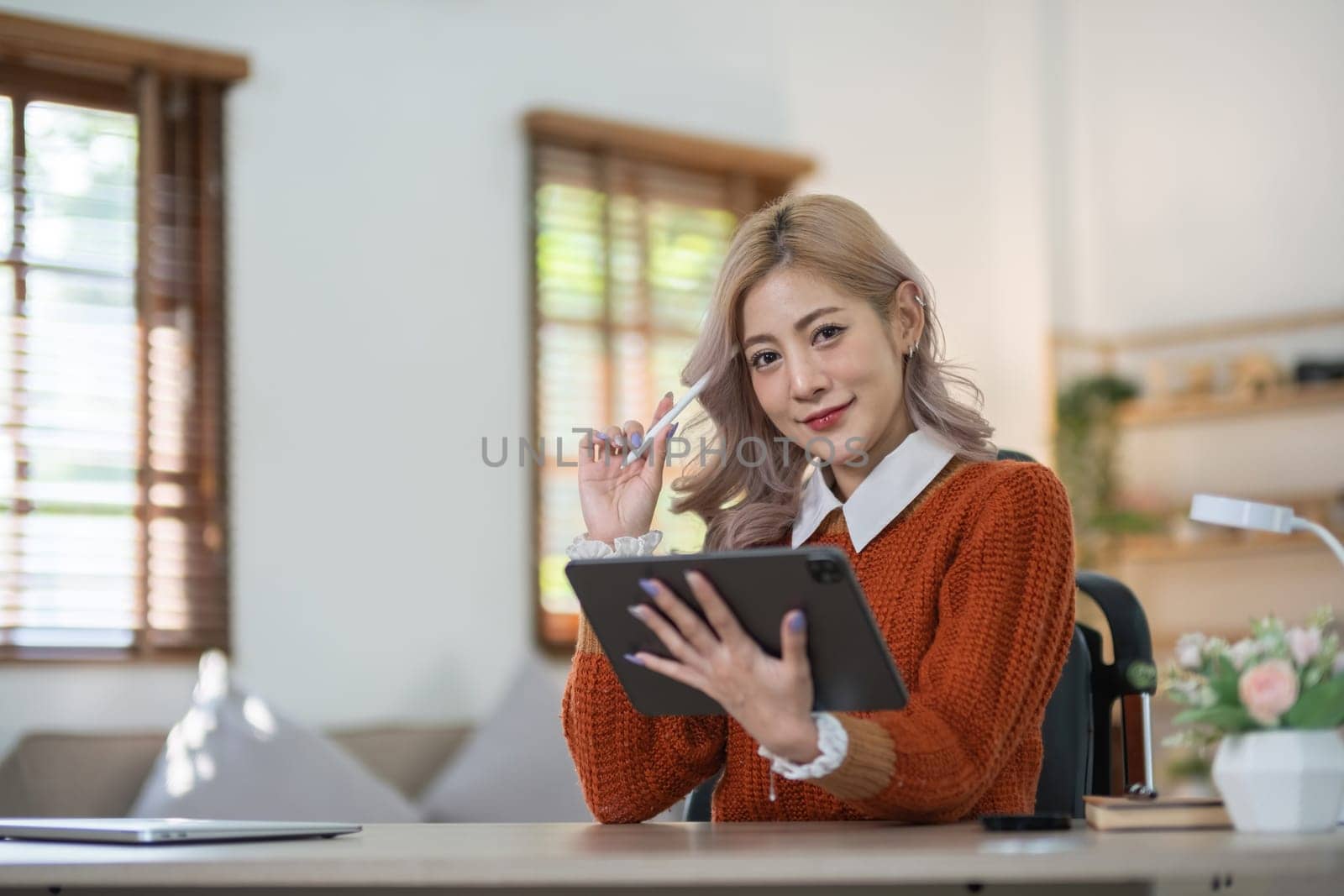 Young beautiful Asian woman is exploring social media in the living room on vacation at home. by wichayada