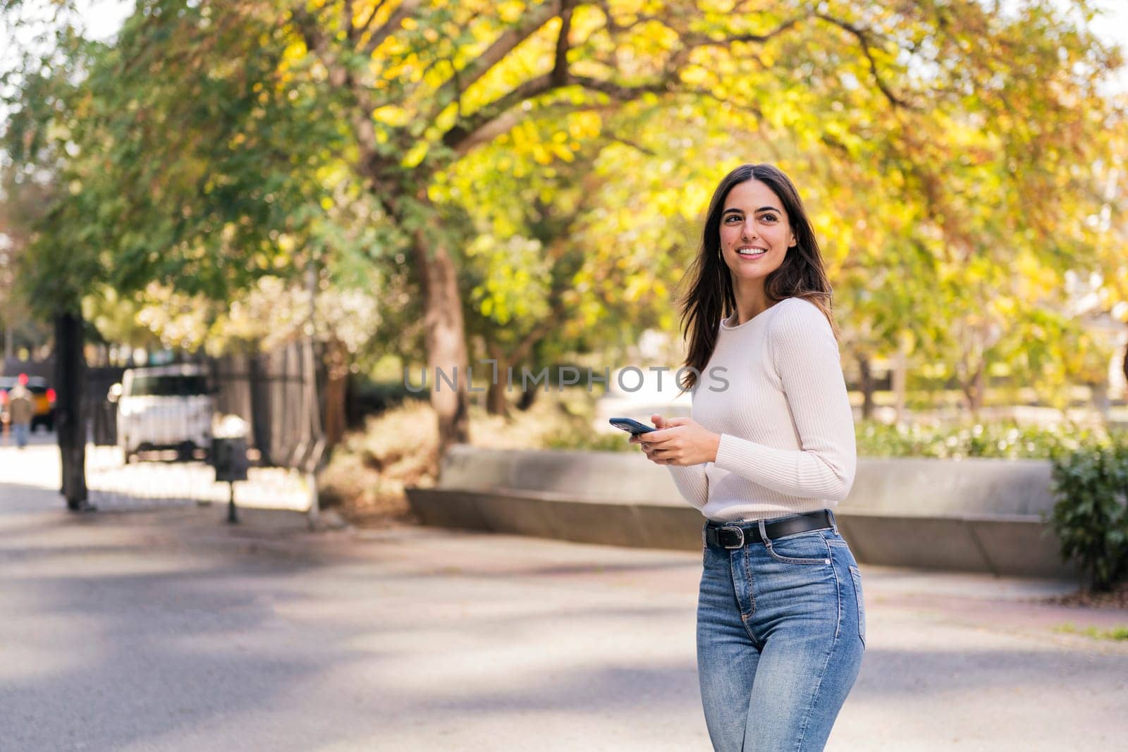 brunette woman smiling happy using her mobile phone, concept of technology of communication and modern lifestyle, copy space for text