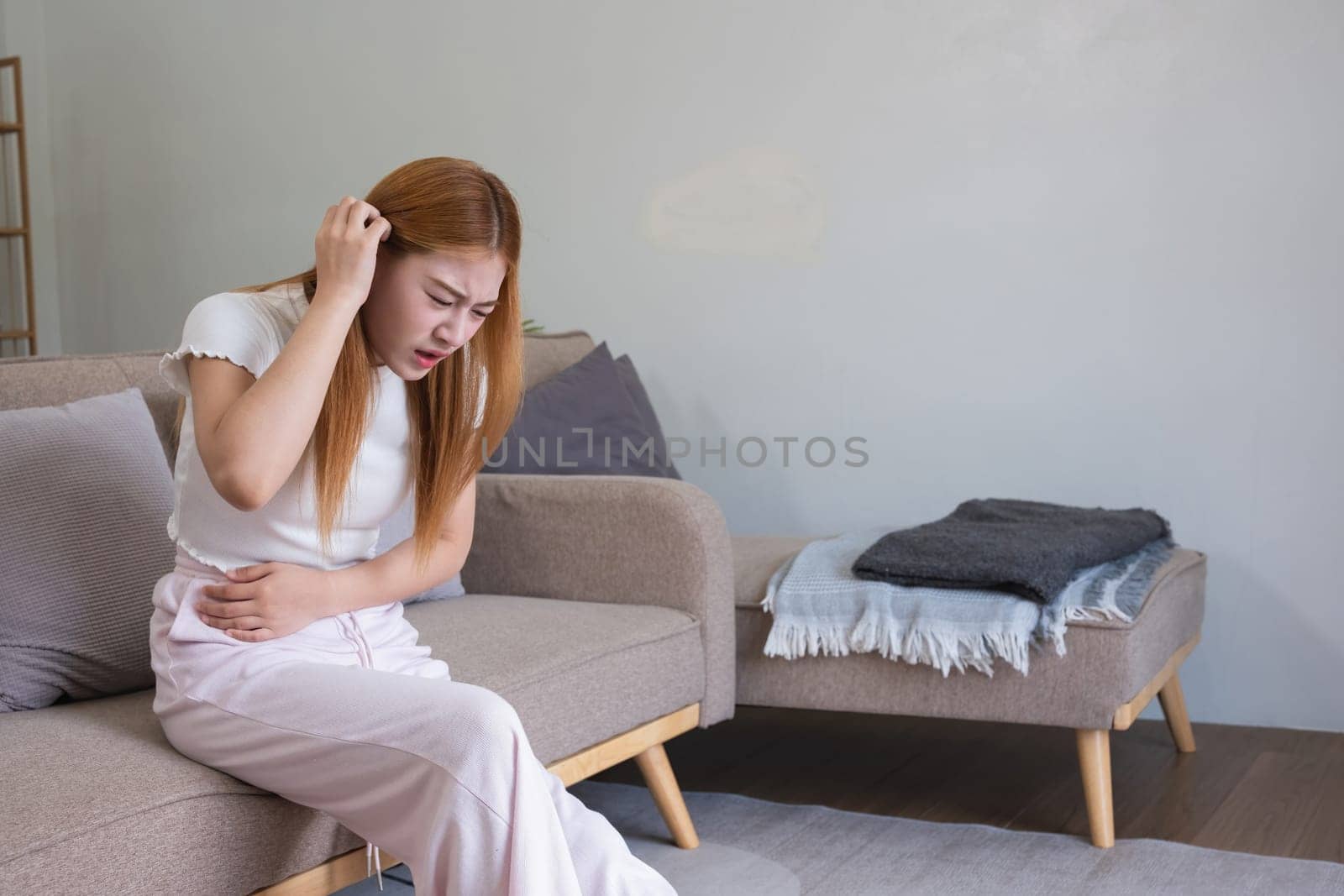 A young Asian woman with abdominal pain from diarrhea or menstrual cramps felt sick and touched her stomach with an unhappy expression. by wichayada