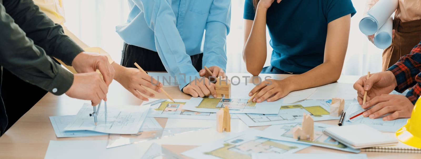Professional architect team plans to build eco house at meeting table with green design document and architectural equipment scatter around. Living and design concept. Closeup. Delineation.