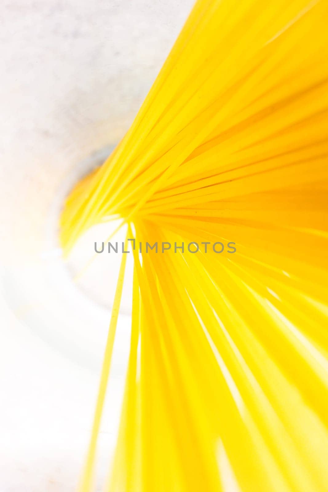 Glass with yellow spaghetti cluster on white surface by clusterx