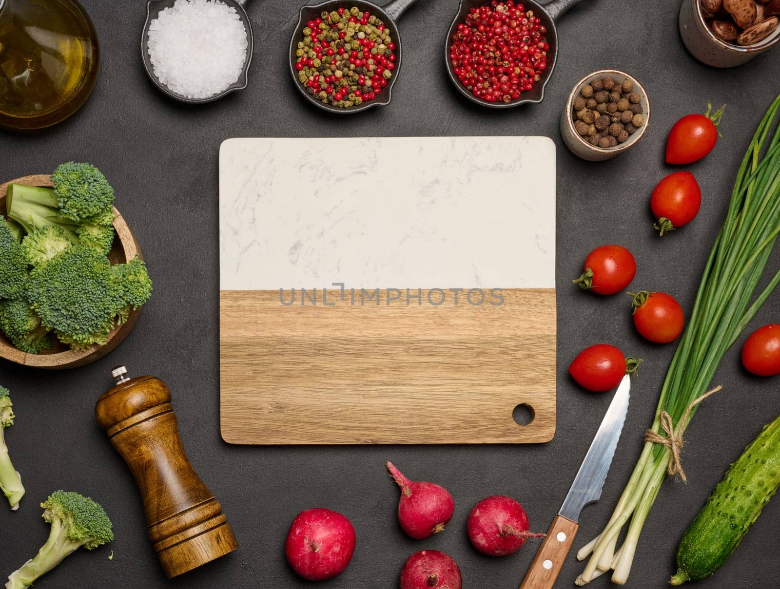 Green lettuce, broccoli, radishes and tomatoes on a black table. Salad ingredients. Copy space 