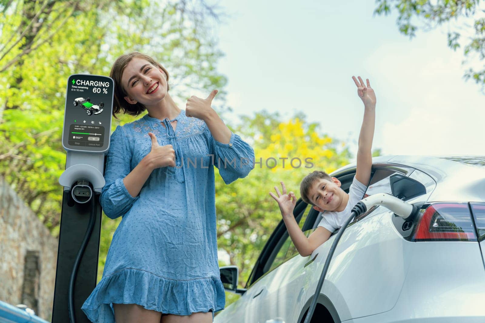 Family road trip vacation with electric vehicle, mother and son recharge EV car with green and clean energy. Nature and travel with eco-friendly car for sustainable environment. Perpetual