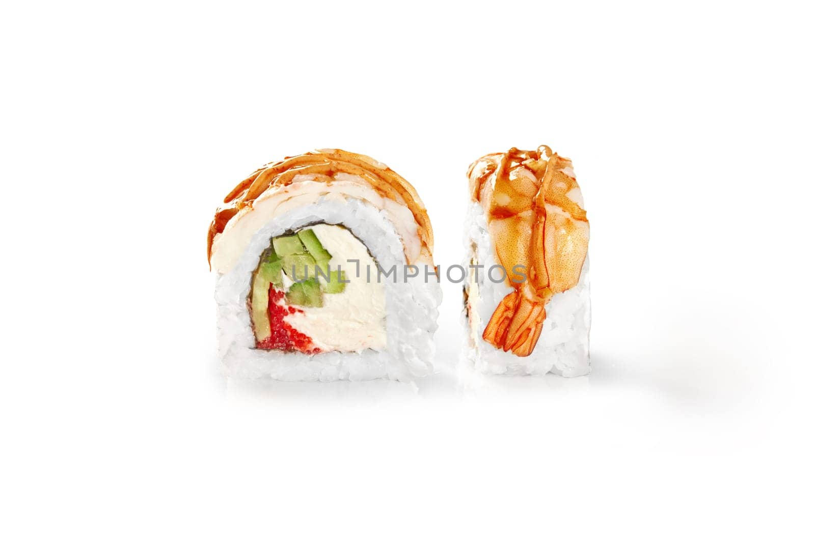 Closeup of shrimp-topped sushi roll drizzled with tangy sauce, filled with soft cream cheese, tobiko and crisp cucumber, presented isolated on white background. Japanese style snack