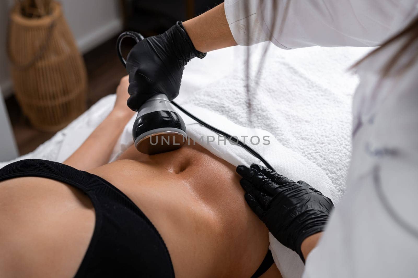 Masseur performs figure correction with ultrasonic cavitation. Spa salon offers non-invasive alternative to traditional liposuction on belly