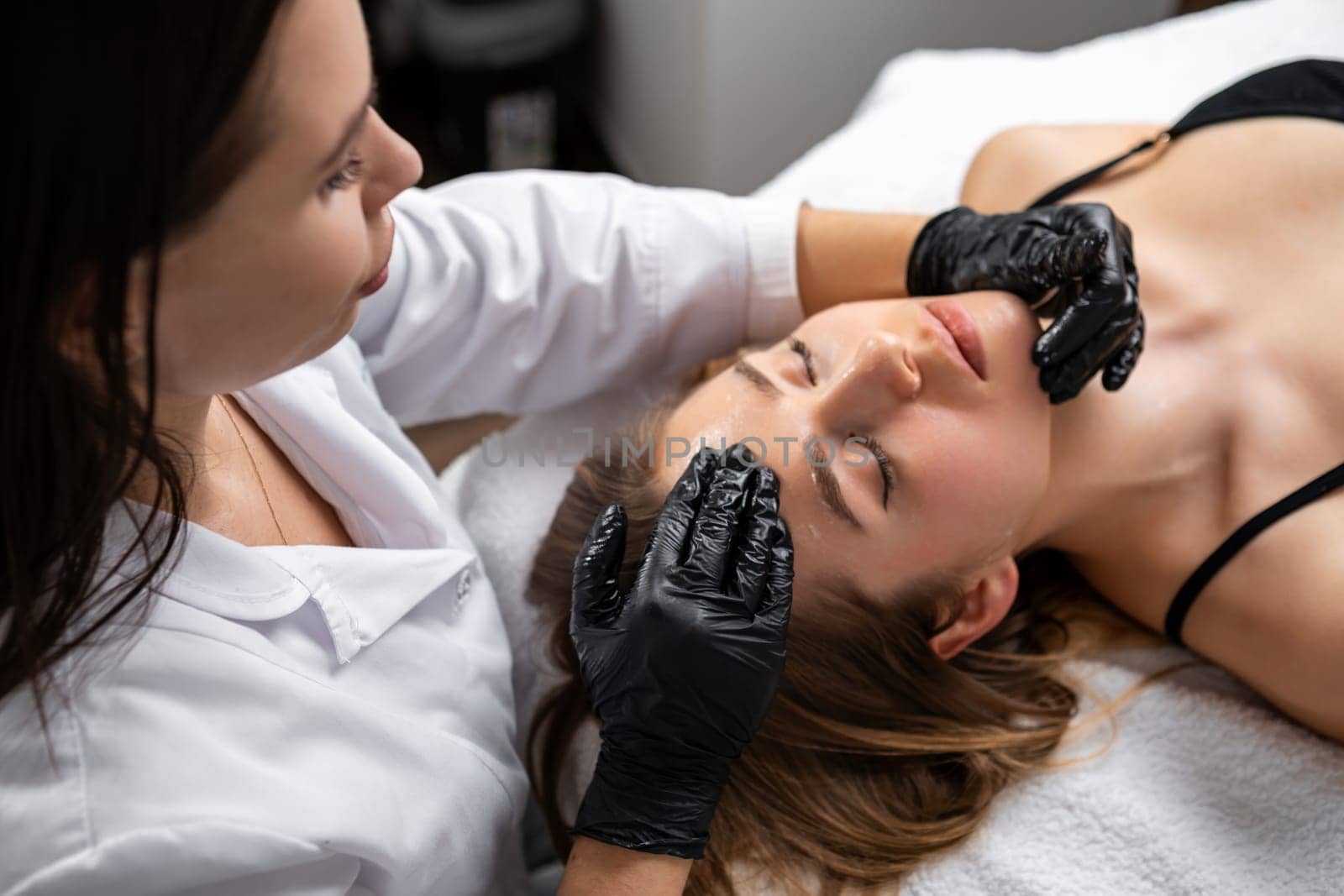 Close up of a young womans face lying and getting face lifting massage.