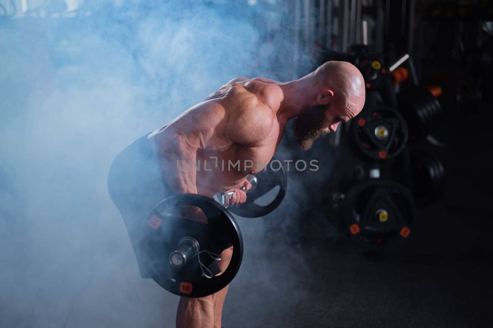 Caucasian bald topless man doing an exercise with a barbell in the gym