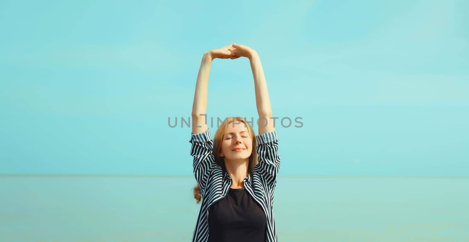 Summer vacation, happy relaxing healthy young woman meditates and enjoying fresh air on the beach on sea coast and blue sky background