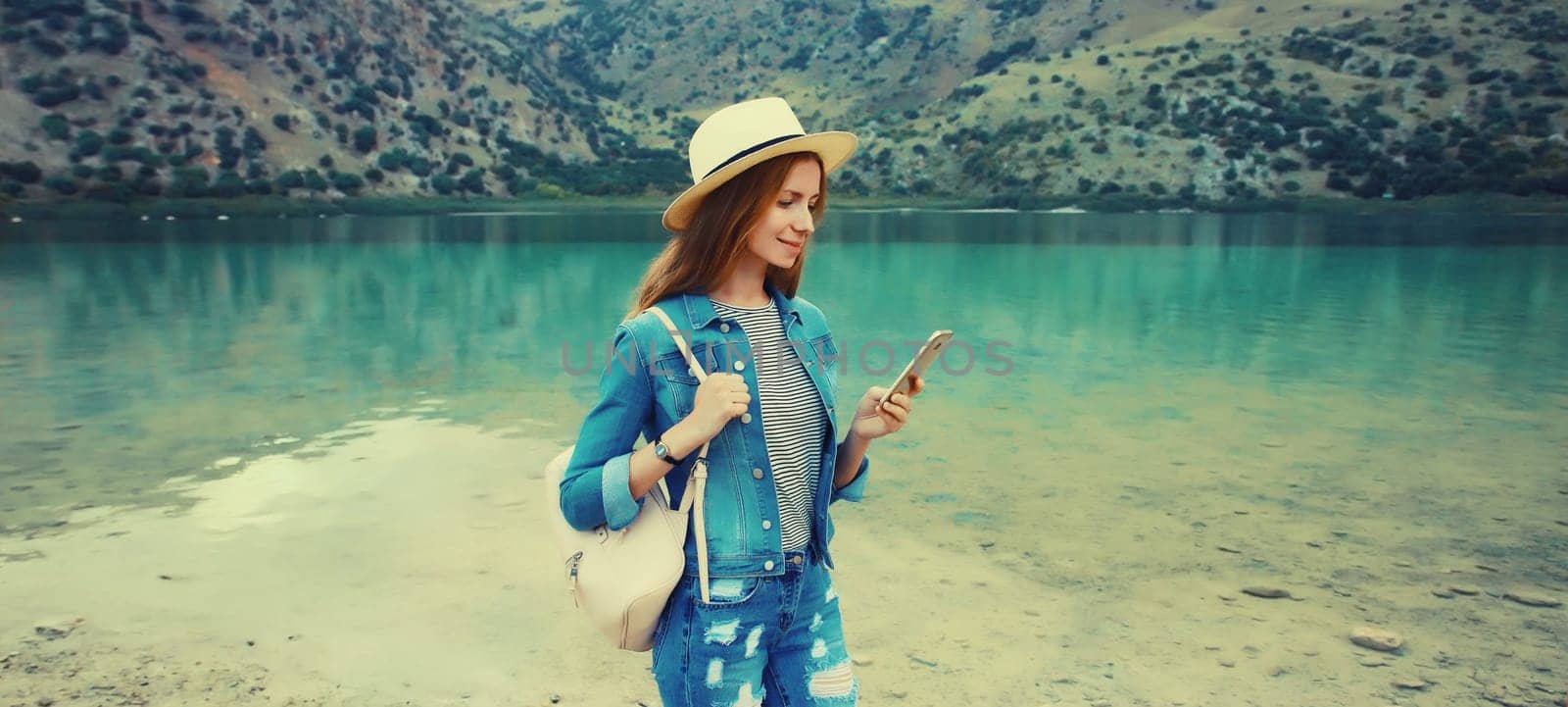 Summer vacation, young woman tourist using phone on lake, mountains background. Greece, island Crete by Rohappy