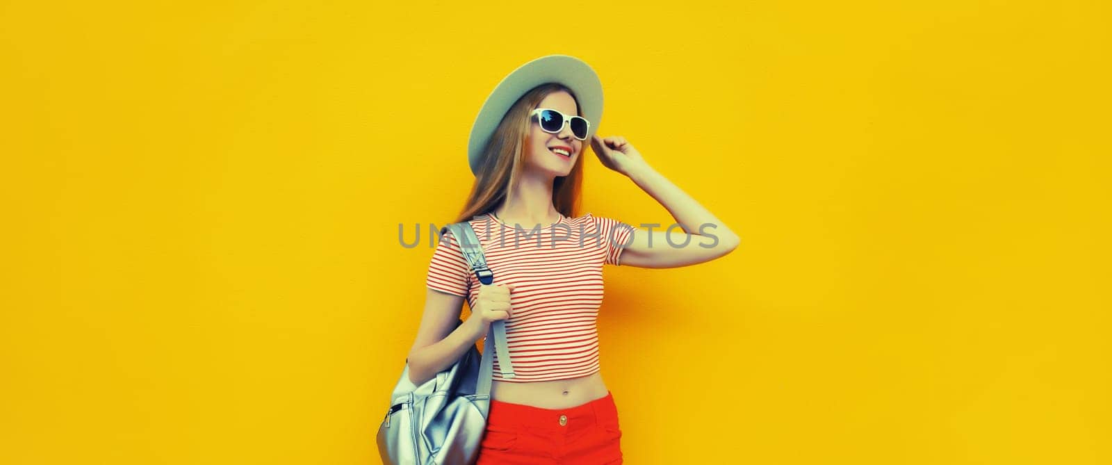 Beautiful young woman posing in summer straw hat, red shorts with backpack by Rohappy
