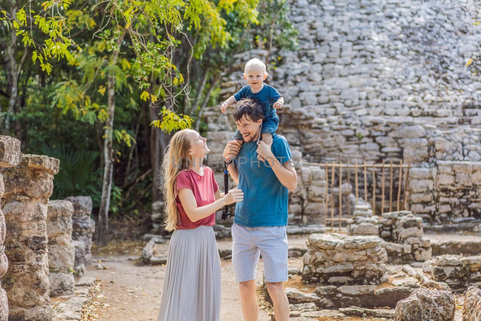 Mom, dad and baby tourists at Coba, Mexico. Ancient mayan city in Mexico. Coba is an archaeological area and a famous landmark of Yucatan Peninsula. Cloudy sky over a pyramid in Mexico.