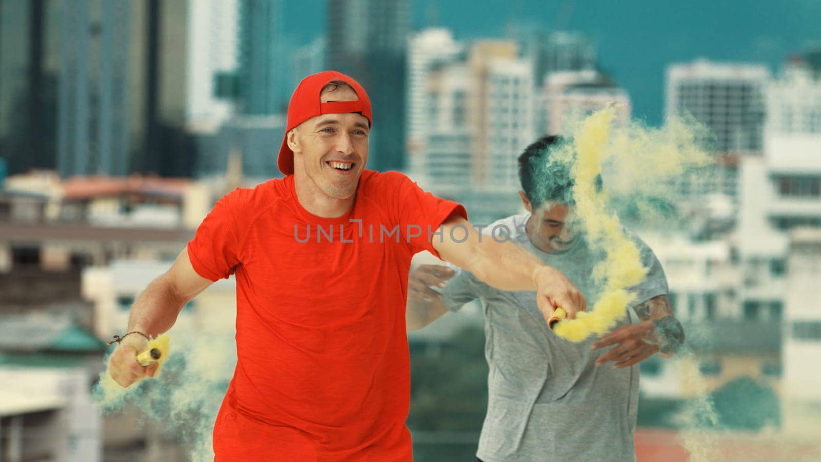 Portrait of caucasian hipster hold yellow smoke flare on roof top at building. Group of break dance practicing performance with sky scrapper Blurring background. Endeavor.