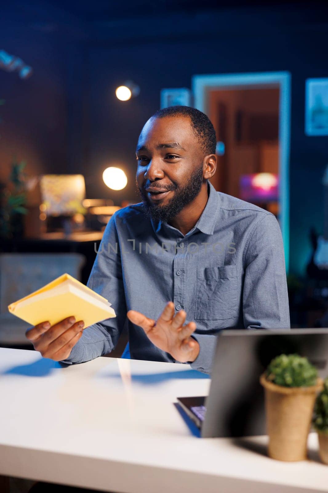 Influencer in studio using camera to capture live broadcast, reviewing new book from publisher. BIPOC online show host filming literature critique, presenting new novel from esteemed author to viewers